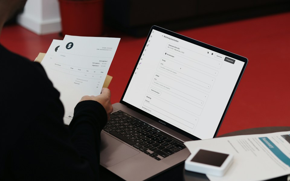 Person reviewing a paper receipt beside an online invoicing system