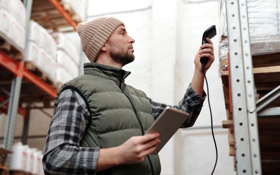 Worker scanning products stored on a warehouse shelf